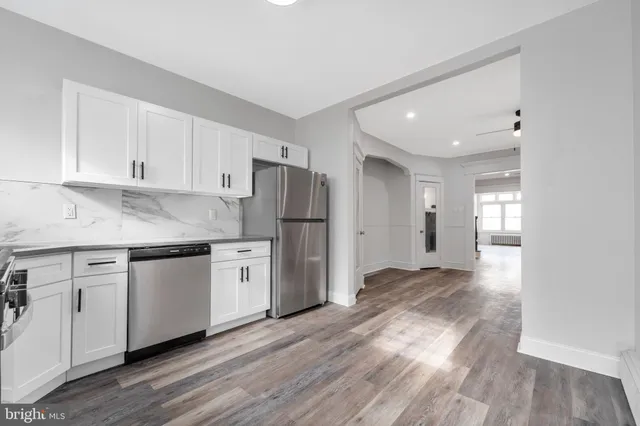 a kitchen with granite countertop a refrigerator sink and white cabinets