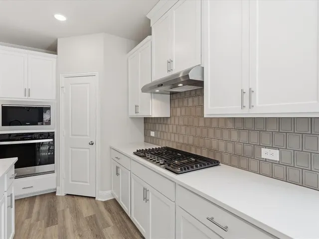 a kitchen with granite countertop a sink a counter top space stainless steel appliances and cabinets