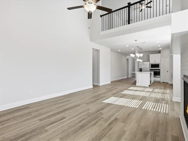 a view of an empty room with wooden floor fireplace and a window
