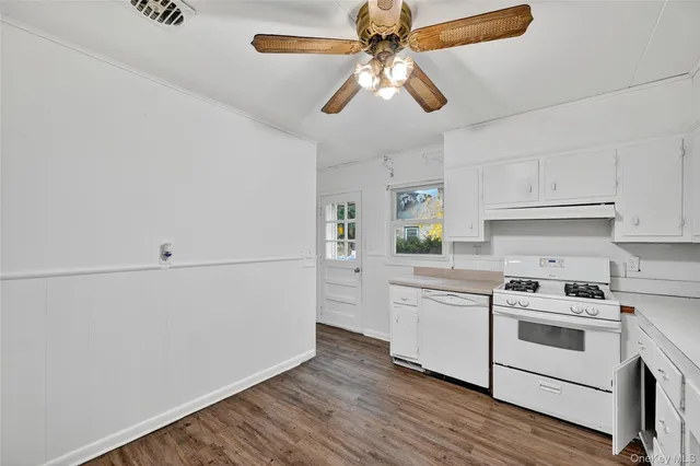 a kitchen with stainless steel appliances white cabinets and wooden floor