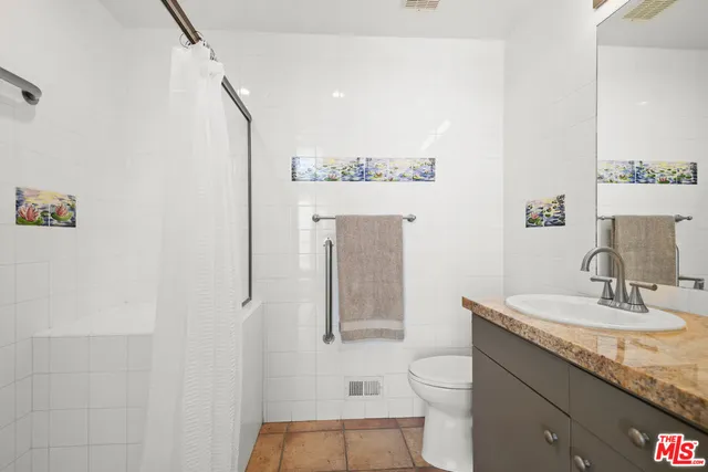 a bathroom with a granite countertop sink toilet and mirror