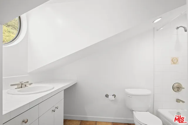 a bathroom with a granite countertop sink and a toilet