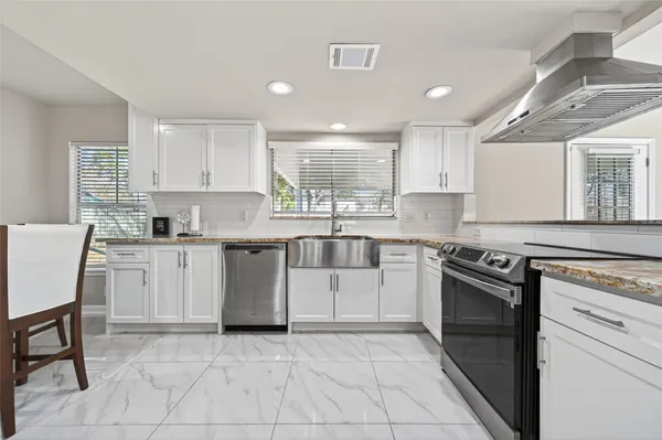 a kitchen with stainless steel appliances granite countertop a refrigerator and a stove top oven