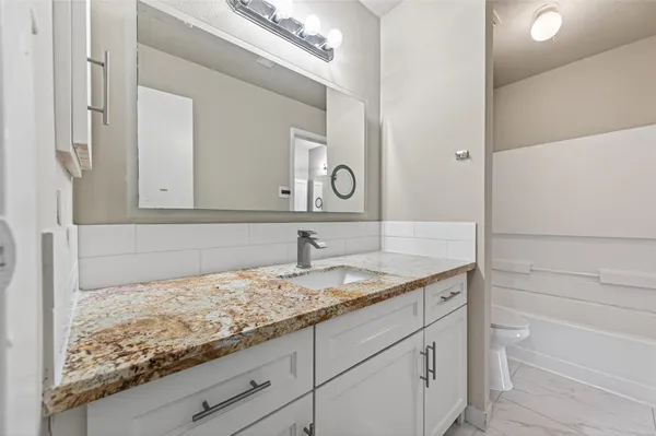 a bathroom with a granite countertop sink and a mirror