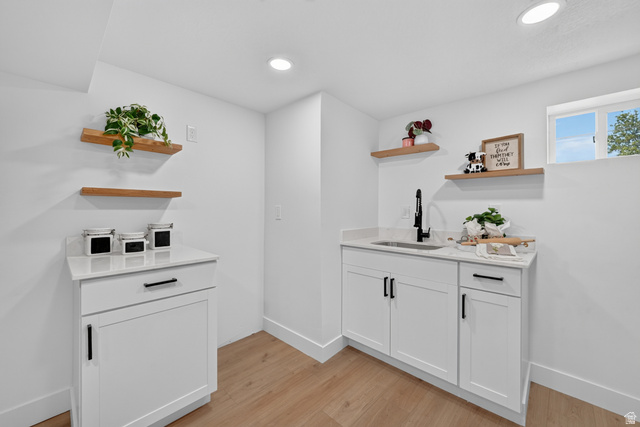 546 West 200 South Payson, UT 84651 - Photo 14 of 45 Dedicated utility space featuring a built-in sink with a matte black faucet, white cabinetry, and light wood-finish flooring
