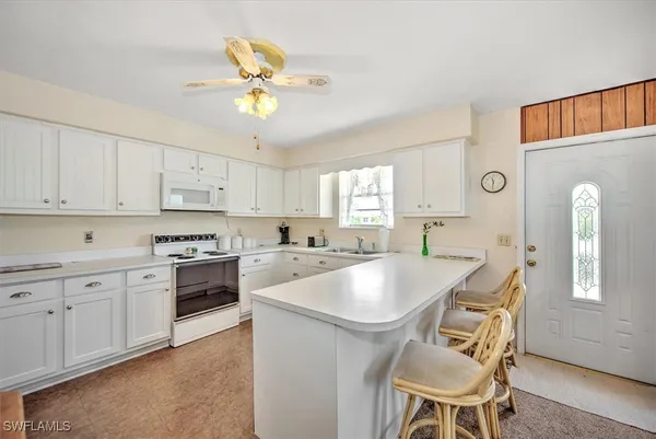 a kitchen with stainless steel appliances granite countertop a white cabinets and chairs