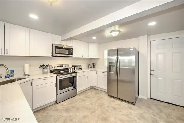 a kitchen with stainless steel appliances granite countertop a refrigerator a stove a sink and a microwave