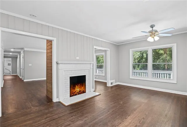 a view of an empty room with wooden floor and a fireplace