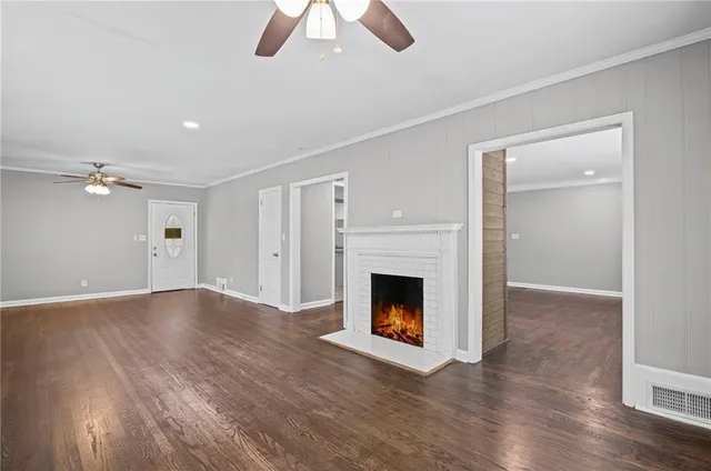 a view of an empty room with wooden floor fireplace and a window