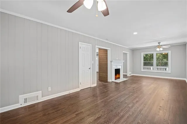 an empty room with wooden floor fireplace and windows