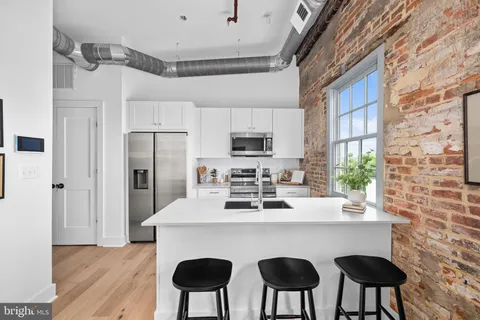 a kitchen with stainless steel appliances a dining table chairs refrigerator and sink