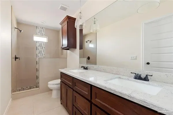 a bathroom with a granite countertop sink a toilet and shower