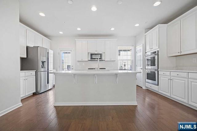 32 Truman Drive Wood-Ridge, NJ 07075 - Photo 18 of 49 a view of a kitchen with stainless steel appliances granite countertop a stove a refrigerator a sink and white cabinets with wooden floor