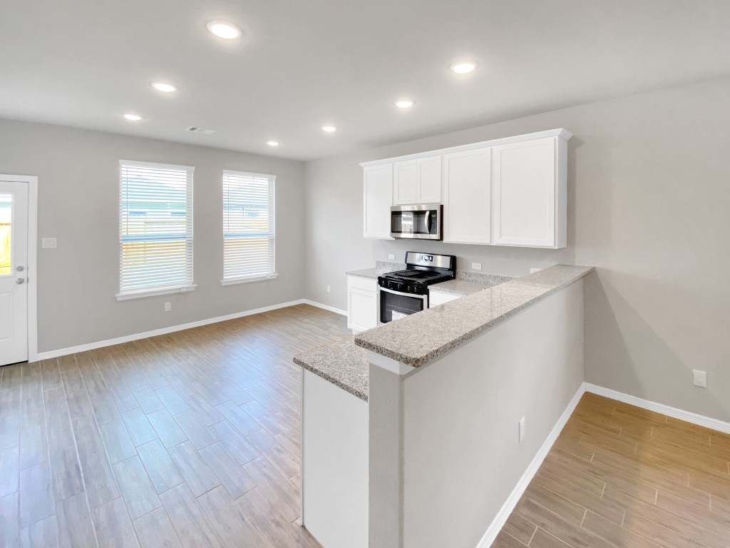 847 Redinger Ridge Drive Huffman, TX 77336 - Photo 7 of 30 a kitchen with kitchen island granite countertop white cabinets and wooden floor