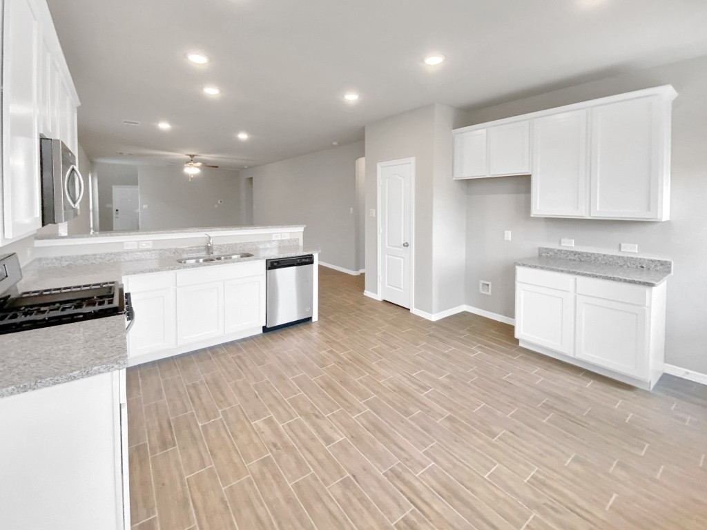 847 Redinger Ridge Drive Huffman, TX 77336 - Photo 9 of 30 a large kitchen with stainless steel appliances a large white kitchen island a two sinks a stove and a wooden floors