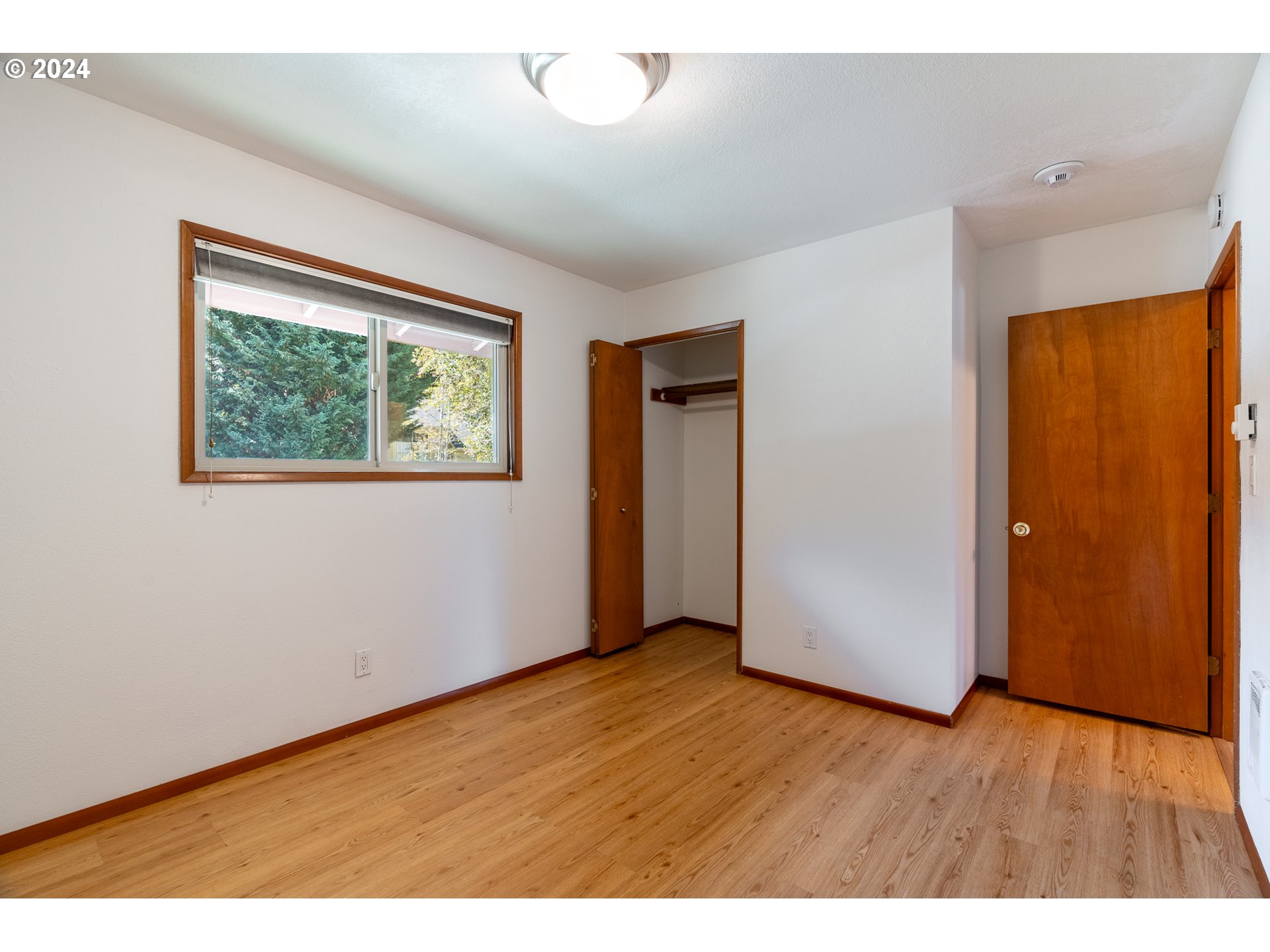5005 Southwest Mitchell Street, Unit 10 Portland, OR 97221 - Photo 11 of 16 a view of an empty room with wooden floor and a window