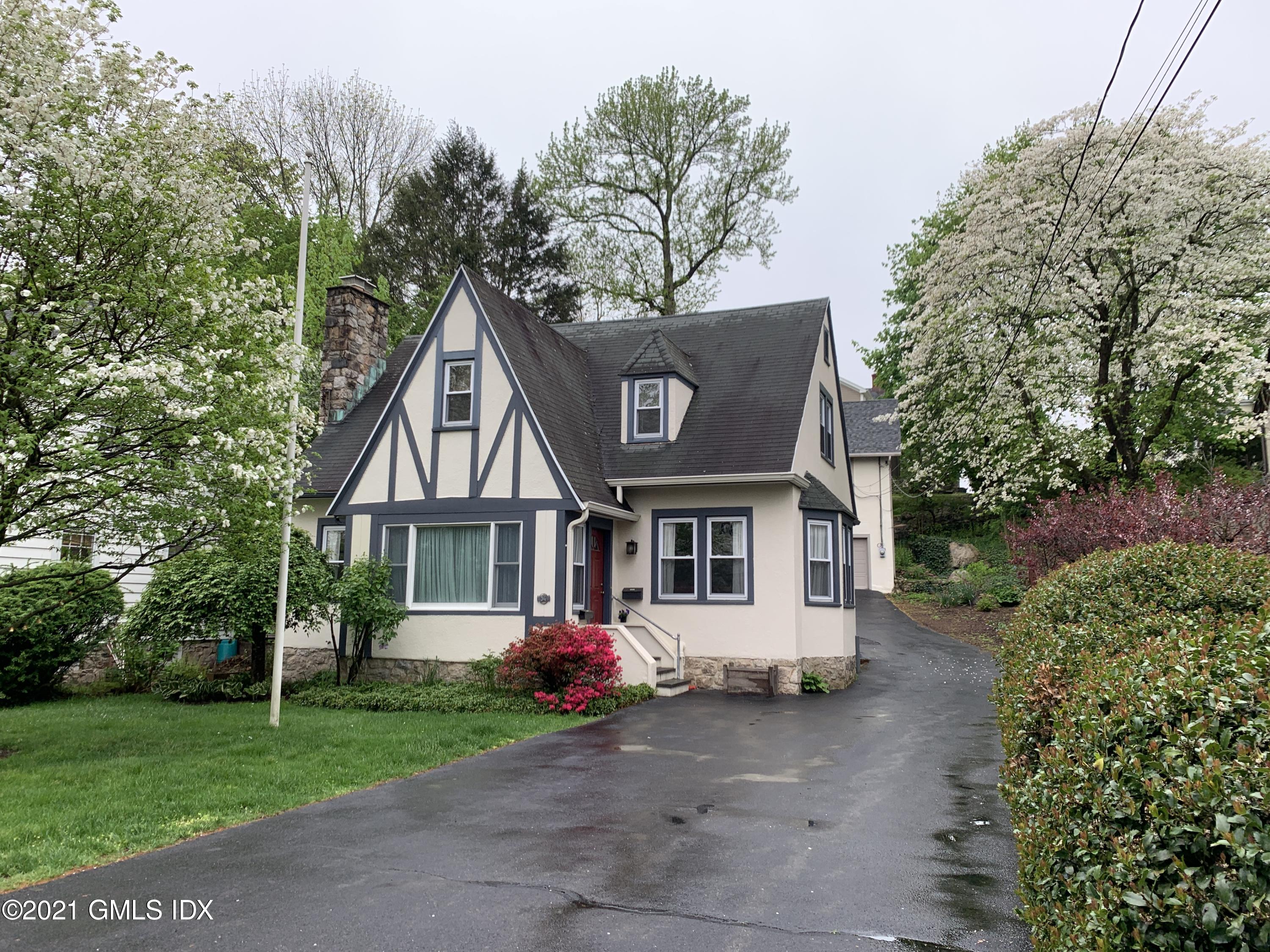 a front view of a house with a garden and trees