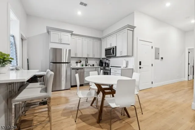 a kitchen with stainless steel appliances kitchen island a table chairs refrigerator sink and cabinets