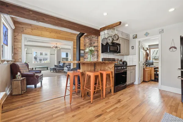 a living room with stainless steel appliances furniture and a wooden floor