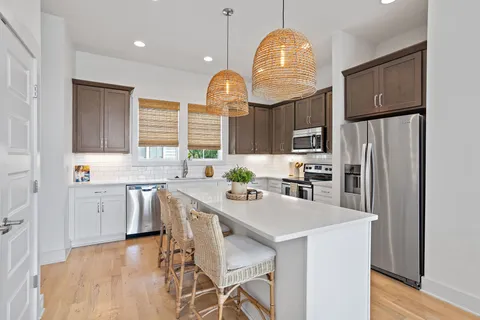 a kitchen with stainless steel appliances granite countertop a stove a refrigerator a sink dishwasher a dining table and chairs with wooden floor