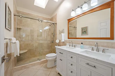 a bathroom with a double vanity sink toilet mirror and shower