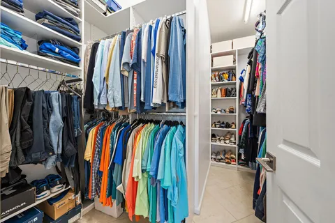 a view of walk in closet with clothes and shoes