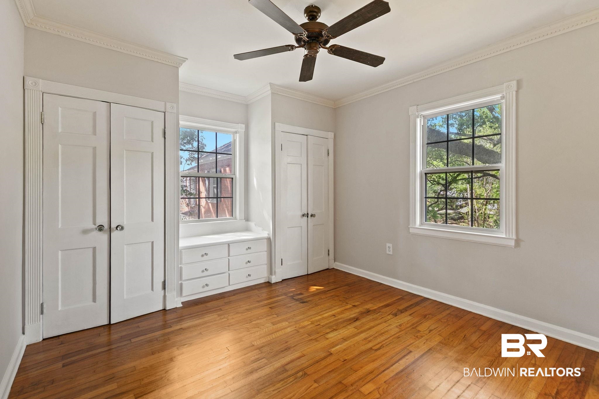 214 Upham Street, Unit 8D Mobile, AL 36607 - Photo 21 of 36 Unfurnished bedroom with multiple closets, light wood-style floors, multiple windows, crown molding, and ceiling fan