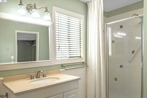 a bathroom with a sink vanity granite shower and a mirror