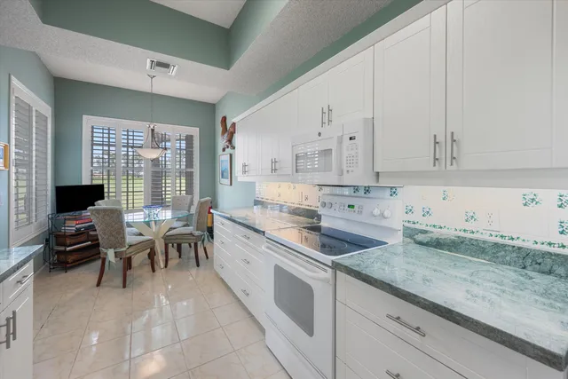 a kitchen with granite countertop a sink white cabinets and white appliances