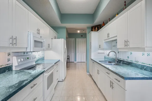 a large white kitchen with granite countertop lots of white cabinets