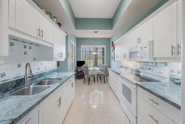 a large white kitchen with a sink and dishwasher a stove with wooden floors
