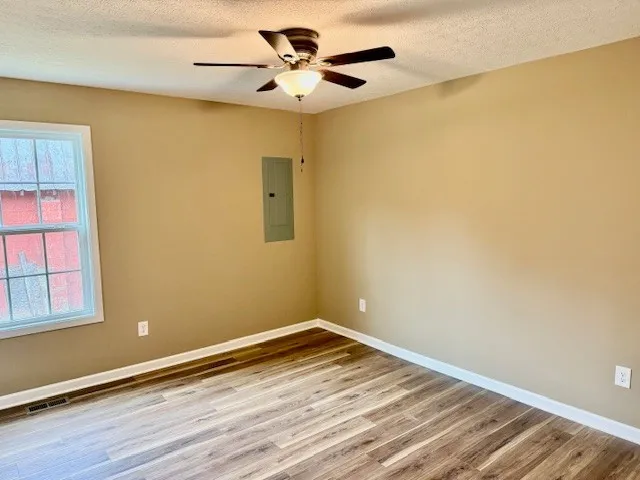 a view of an empty room with wooden floor and a window