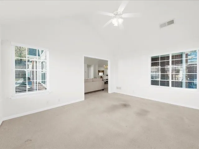 an empty room with a ceiling fan and windows