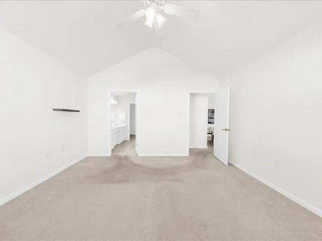an empty room with windows and chandelier fan