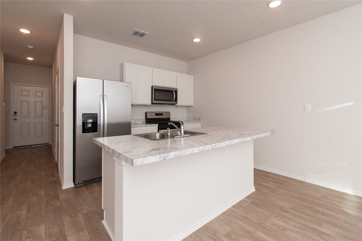 201 Varner Way Lockhart, TX 78644 - Photo 4 of 16 Kitchen with appliances with stainless steel finishes, light countertops, recessed lighting, white cabinetry, and light wood finished floors