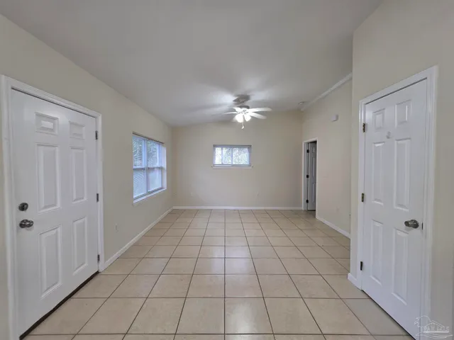 a view of an empty room with window and chandelier fan