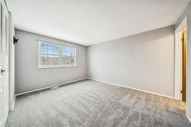 an empty room with windows and refrigerator