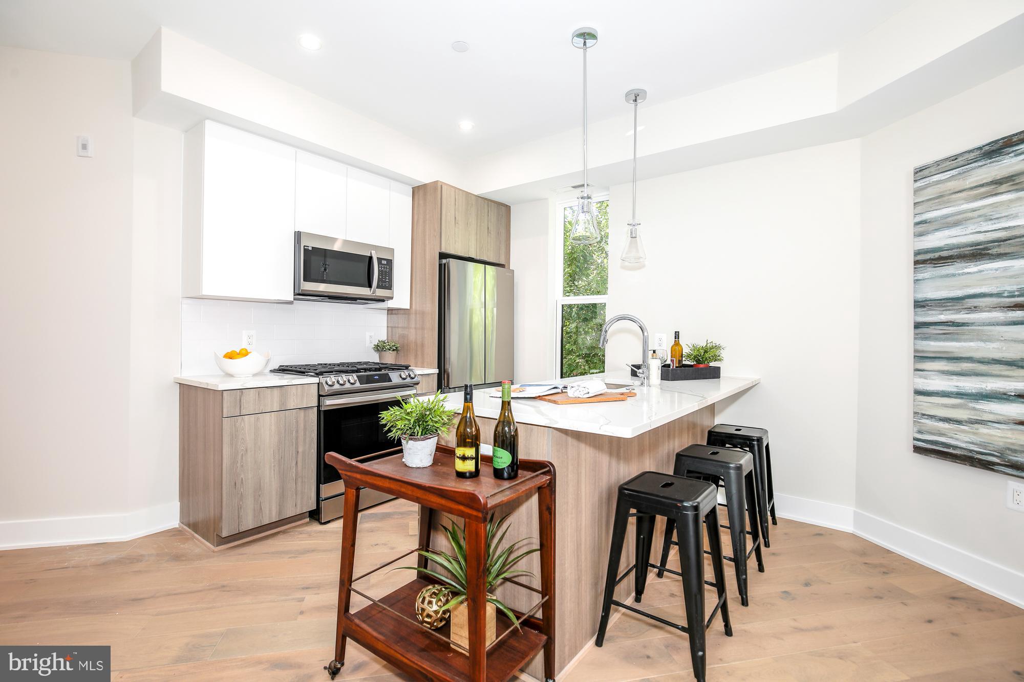 1421 Spring Road Northwest, Unit IZ204 Washington, DC 20010 - Photo 4 of 12 a kitchen with a dining table chairs and refrigerator