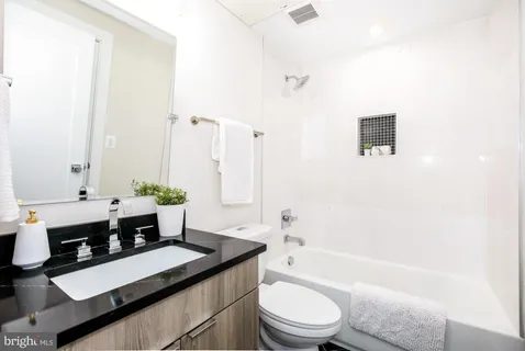 a bathroom with a double vanity sink toilet mirror and bathtub