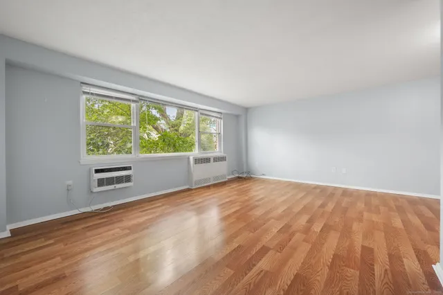 a view of an empty room with a window and a kitchen