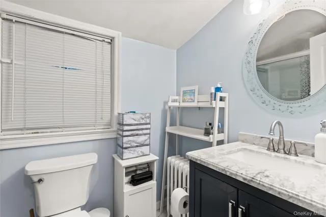 a bathroom with a granite countertop sink a toilet and a mirror