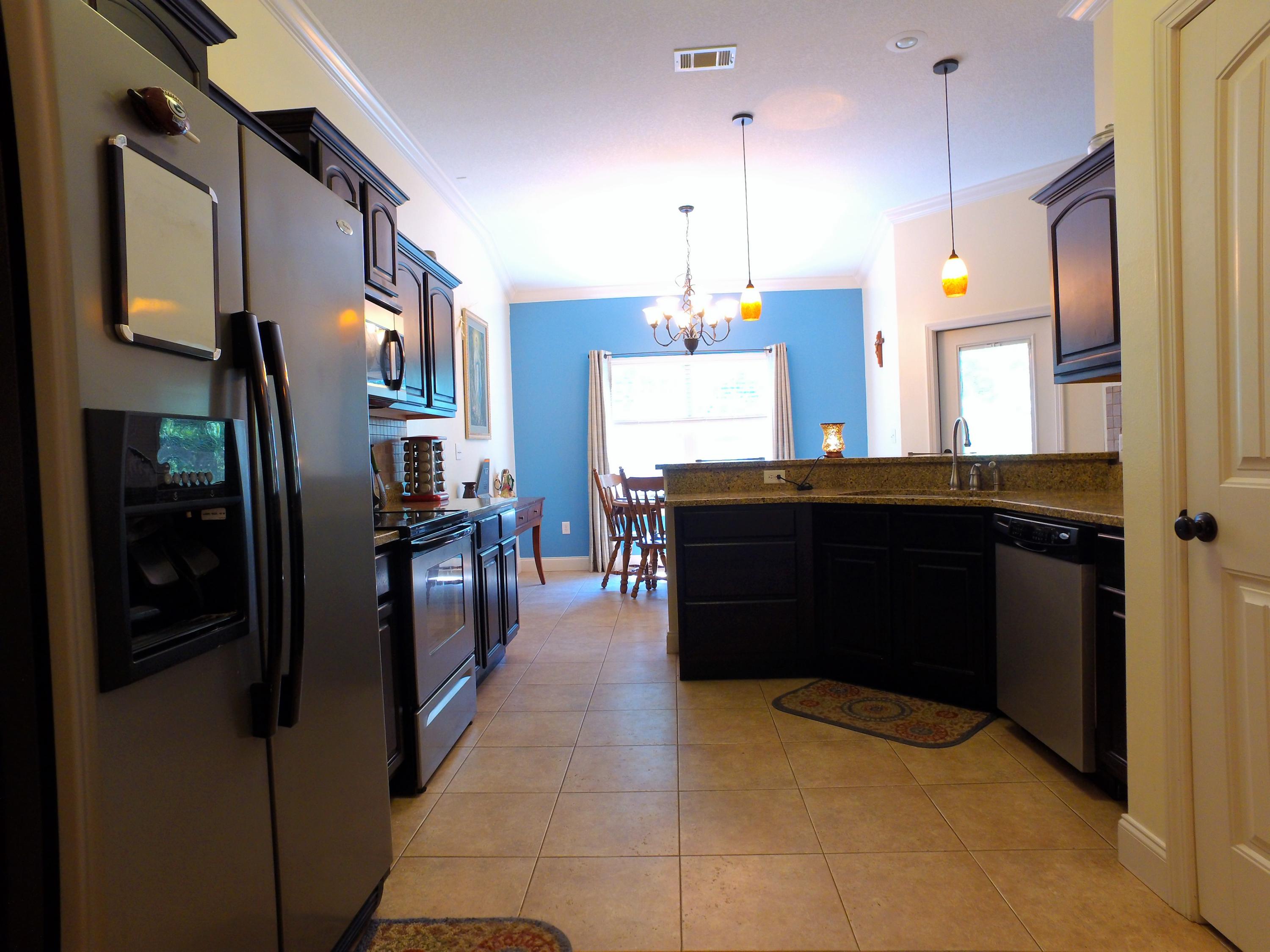 4568 Hermosa Road Crestview, FL 32539 - Photo 7 of 51 a kitchen with stainless steel appliances kitchen island granite countertop a refrigerator and a wooden cabinets