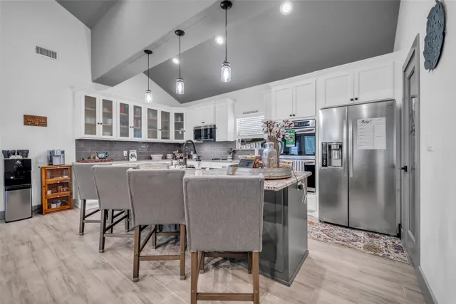 a kitchen with stainless steel appliances granite countertop a chairs a sink a stove a refrigerator cabinets and chairs