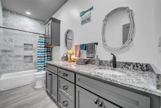 a bathroom with a granite countertop sink mirror and bathtub