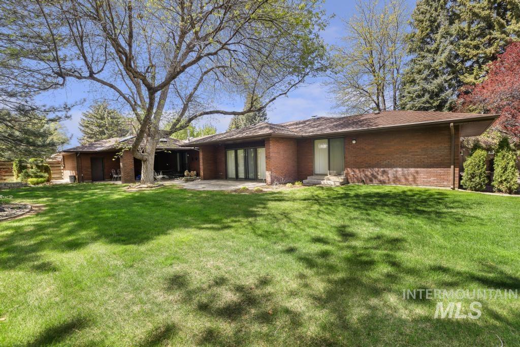 2018 Rancho Vista Drive Twin Falls, ID 83301 - Photo 43 of 50 Expansive green lawn with mature trees and a brick exterior residence featuring a covered patio