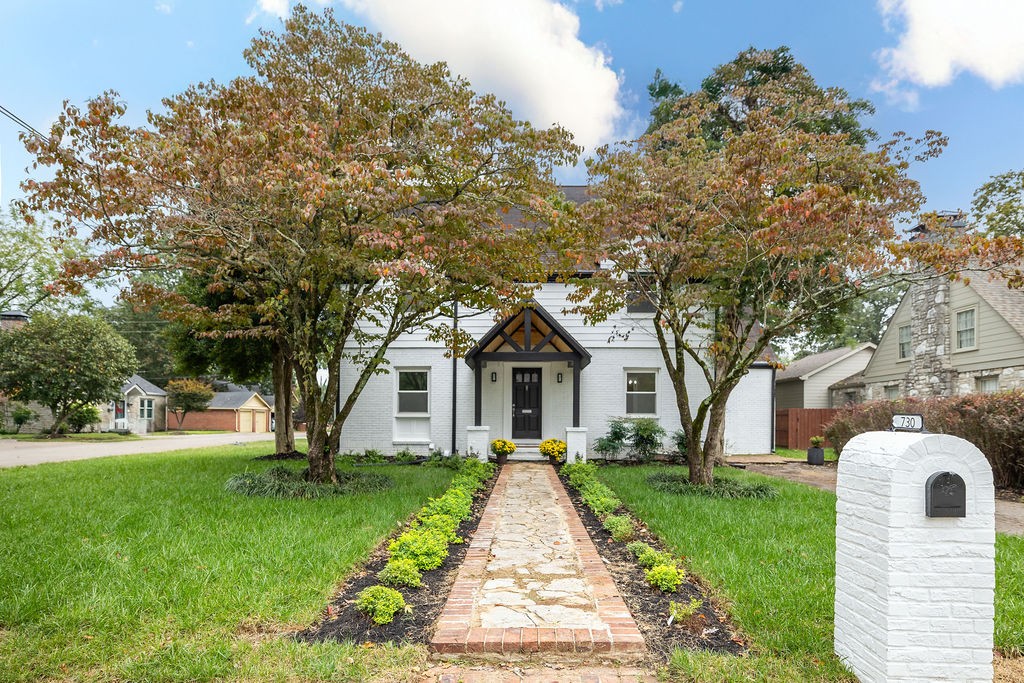 a front view of a house with a garden and tree