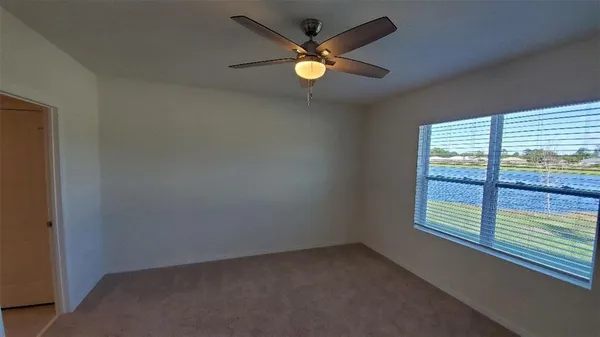 an empty room with ceiling fan and window