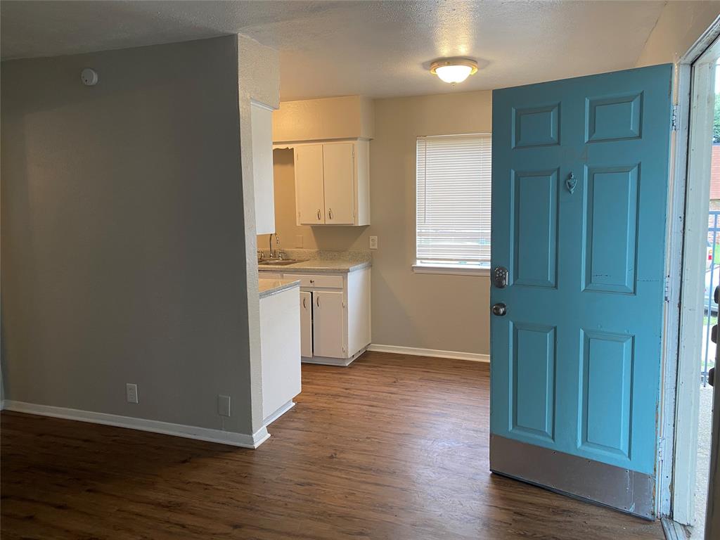 4606 Monarch Street, Unit 104 Dallas, TX 75204 - Photo 3 of 13 Kitchen featuring dark wood finished floors, white cabinets, a textured ceiling, and light stone counters