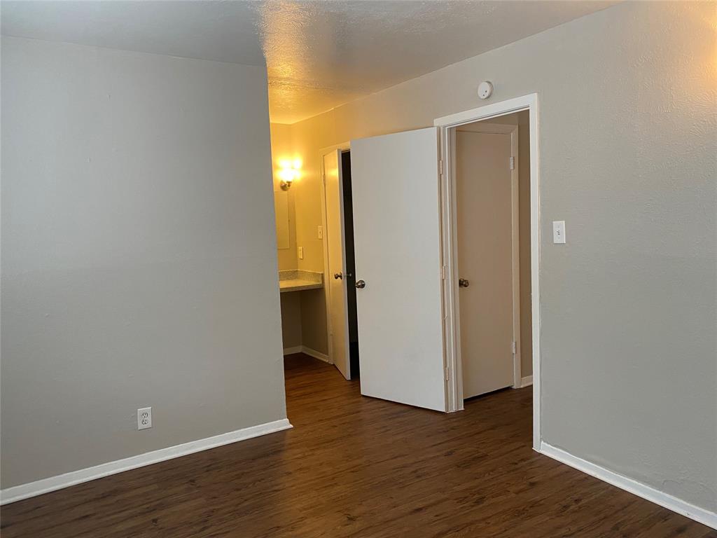 4606 Monarch Street, Unit 104 Dallas, TX 75204 - Photo 6 of 13 Unfurnished room featuring dark wood-style floors and a textured ceiling