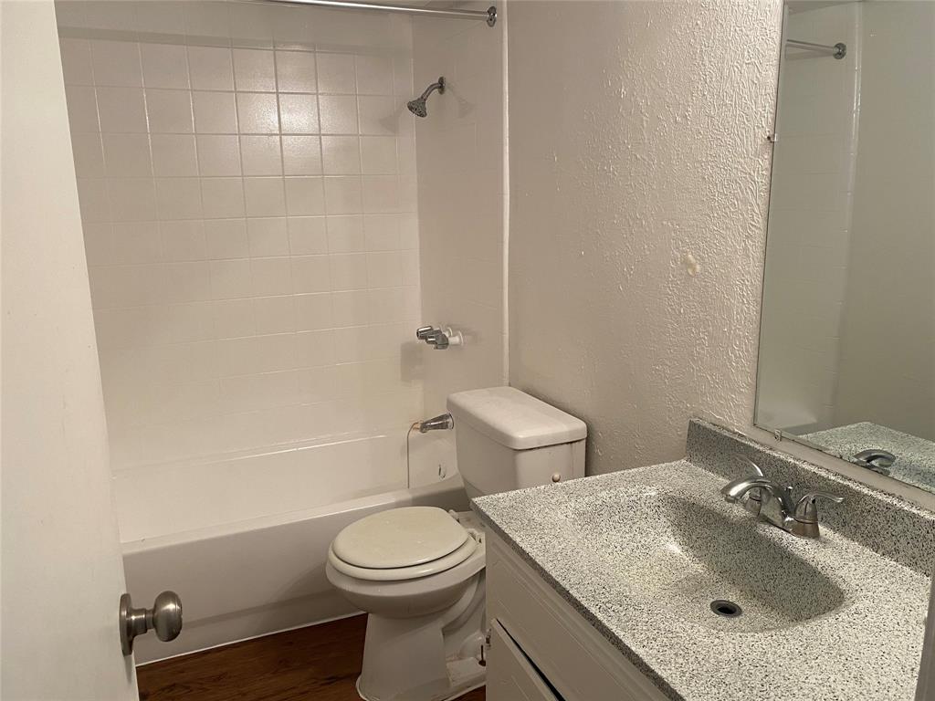 4606 Monarch Street, Unit 104 Dallas, TX 75204 - Photo 9 of 13 Bathroom with vanity, shower combination, dark wood finished floors, and a textured wall